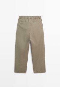 Pantalon beige à jambes droites avec poches passepoilées au dos et taille élastique avec passants pour ceinture, montré de dos sur fond blanc.