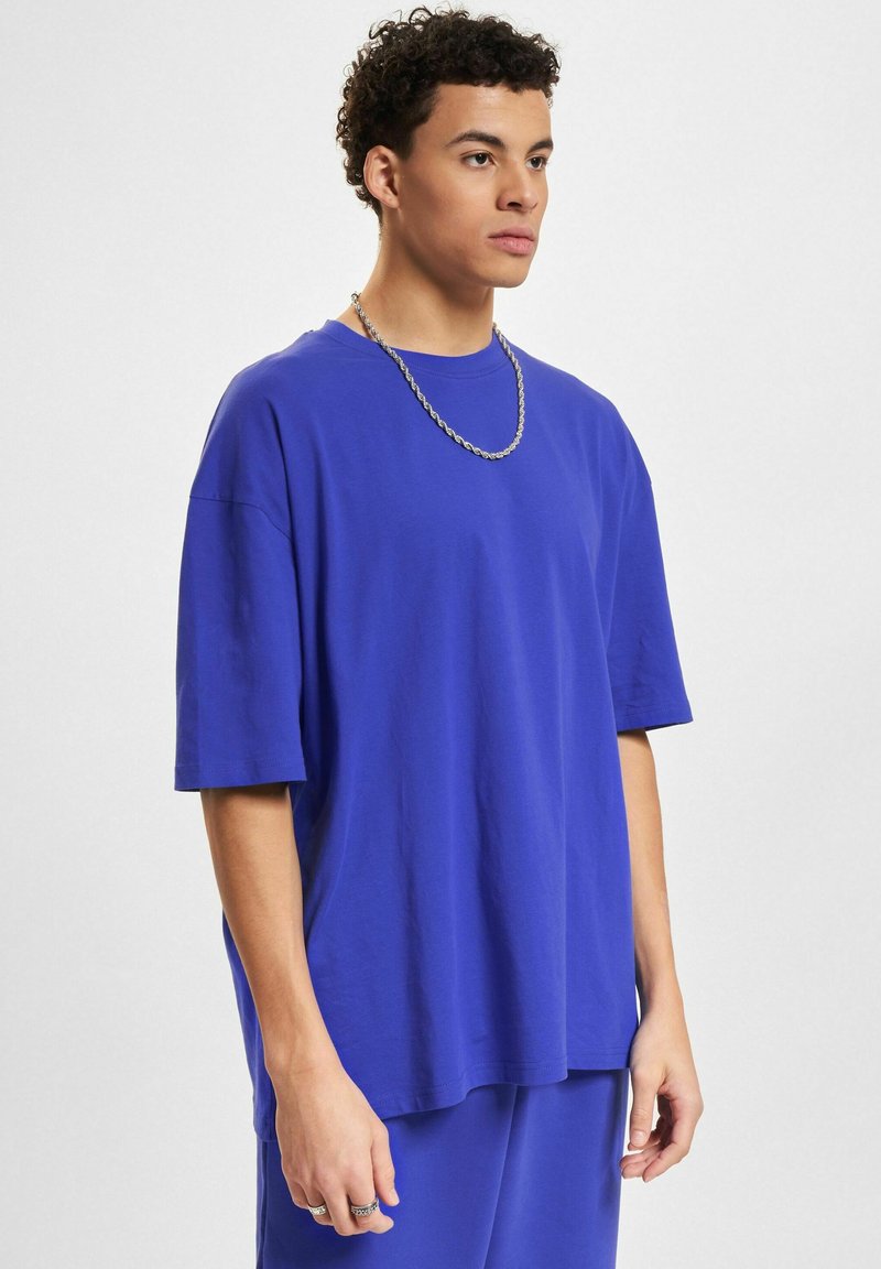 Koninklijk blauwe katoenen t-shirt met korte mouwen en een relaxte pasvorm. Heeft een ronde hals en een gladde textuur. Draag het met een zilveren ketting.