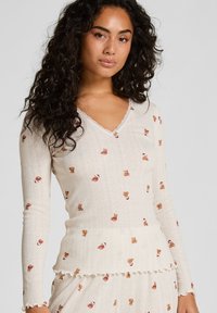 Langemouwen, crèmekleurige v-hals top van textuurstof, met geborduurde teddybeerpatronen en Schulpafwerkingen.