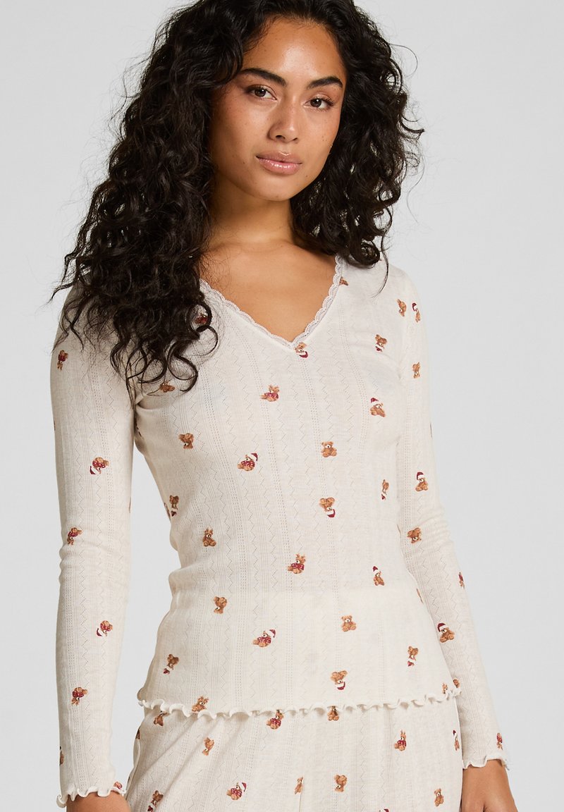 Langemouwen, crèmekleurige v-hals top van textuurstof, met geborduurde teddybeerpatronen en Schulpafwerkingen.