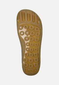 Transparent rubber shoe sole featuring circular grip patterns and raised lines. Branding visible in bold text. Color: amber.