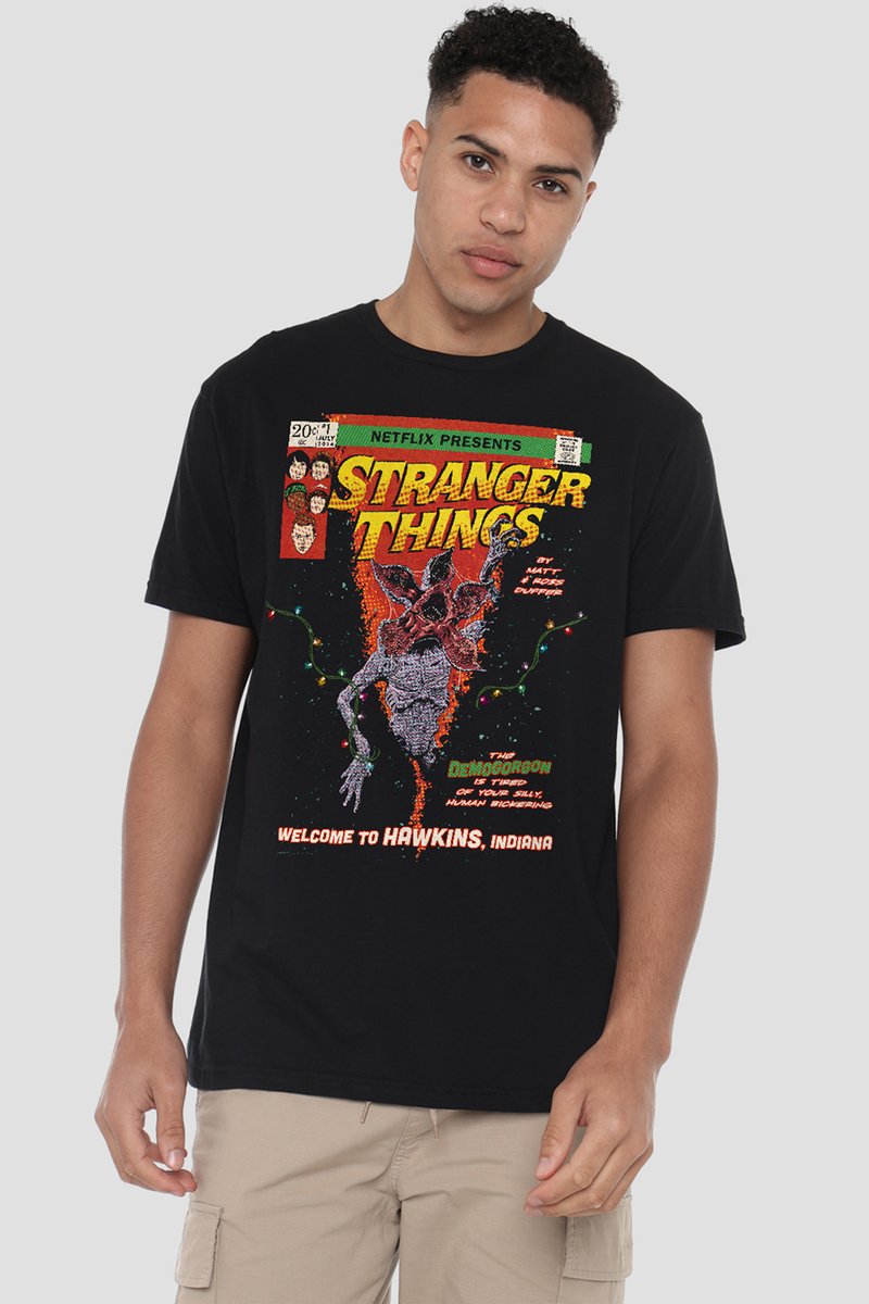 Young man wearing black Stranger Things t-shirt featuring the Demogorgon, colorful lights, and text about Hawkins, Indiana.