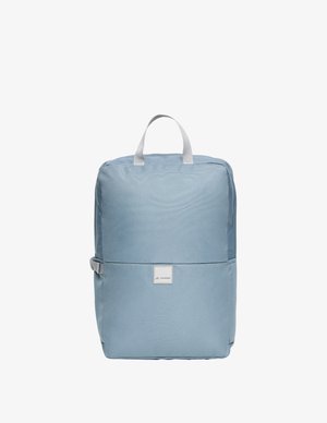 Mochila rectangular de color azul claro con asa superior, correa lateral y una pequeña etiqueta frontal con el nombre de la marca "Vaude".