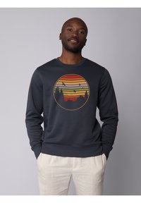Sweatshirt en coton bleu marine à manches longues, avec un motif circulaire de coucher de soleil dans des teintes d'orange, rouge et jaune, et une silhouette noire d'arbres.