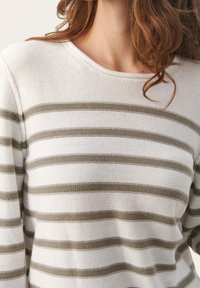 Raidallinen neulevalkoisen ja oliivivihreän vaakaraitojen yhdistelmä, jossa on rento kaula-aukko ja teksturoitu neulottu kangas.