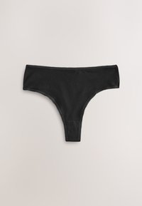 Braguitas tipo tanga de algodón negro con encaje en la cintura y las aberturas de las piernas, sobre un fondo claro y liso.