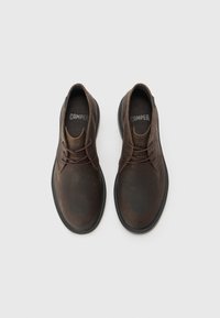 Brown leather shoes with a smooth texture, round toe, and black rubber sole. Features lace-up design and brand name printed inside.