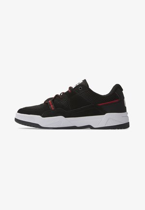 Zapatillas deportivas negras que combinan materiales de malla y ante, con acentos rojos, una entresuela blanca y una suela de goma texturizada para ofrecer tracción.