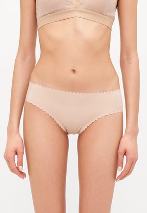 Beige undertøy med bølgemønster på kanten, som har en glatt tekstur og sømløst design, og gir en minimalisme som passer til hverdagsbruk.