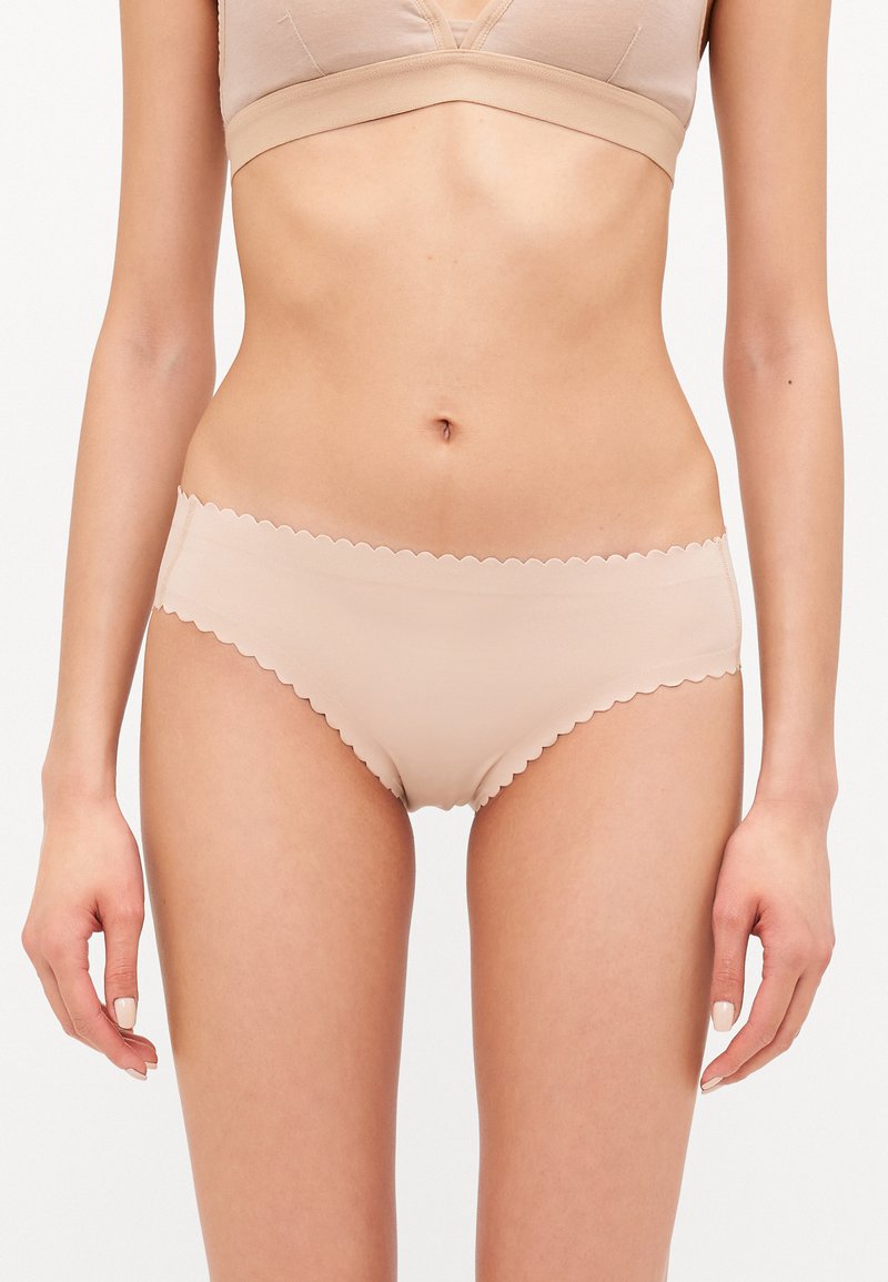 Mutande beige con bordo scallop, caratterizzate da una texture liscia e un design senza cuciture, che offrono uno stile minimalista adatto all'uso quotidiano.
