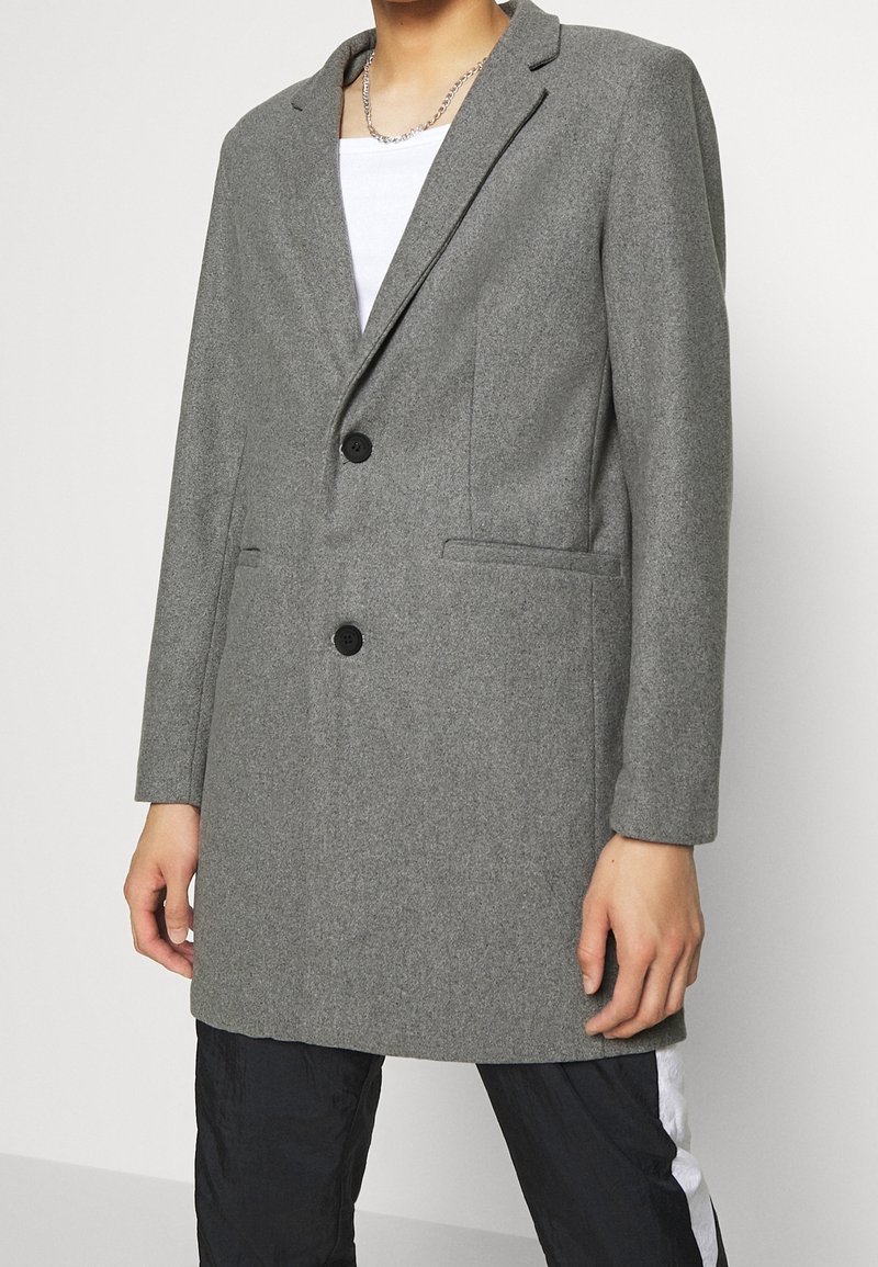 Grijze blazer van een wolmix met reverkragen, dubbele knoopsluiting en twee voorzakken. Heeft een getailleerde pasvorm en een gladde textuur.