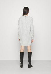 Abito maglione grigio con maniche lunghe, scollatura rotonda e dettaglio con zip sul retro. Realizzato in morbido tessuto a maglia, termina sopra il ginocchio.