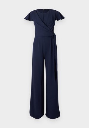 Combinaison bleu marine avec manches courtes volantées, design croisé, pantalons larges et détail de nœud sur le côté. Confectionnée en tissu lisse.