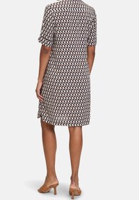 Kratké šaty s krátkým rukávem ve vzorované látce s geometrickými tvary v hnědých, béžových a námořnických barvách, se rovnou spodní části a volným střihem.
