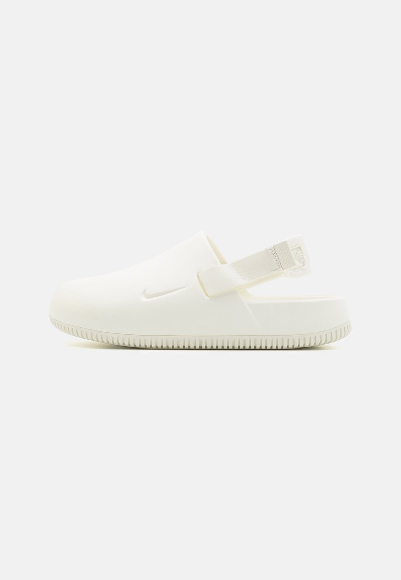 Zueco blanco de espuma con correa, que presenta una suela texturizada y un diseño minimalista. Logo de Nike estampado en el lado superior.