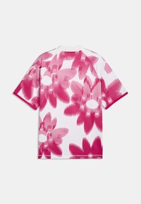 Chemise blanche à manches courtes avec un motif floral abstrait rose et des détails de lignes diagonales, vue de dos sur un fond uni.