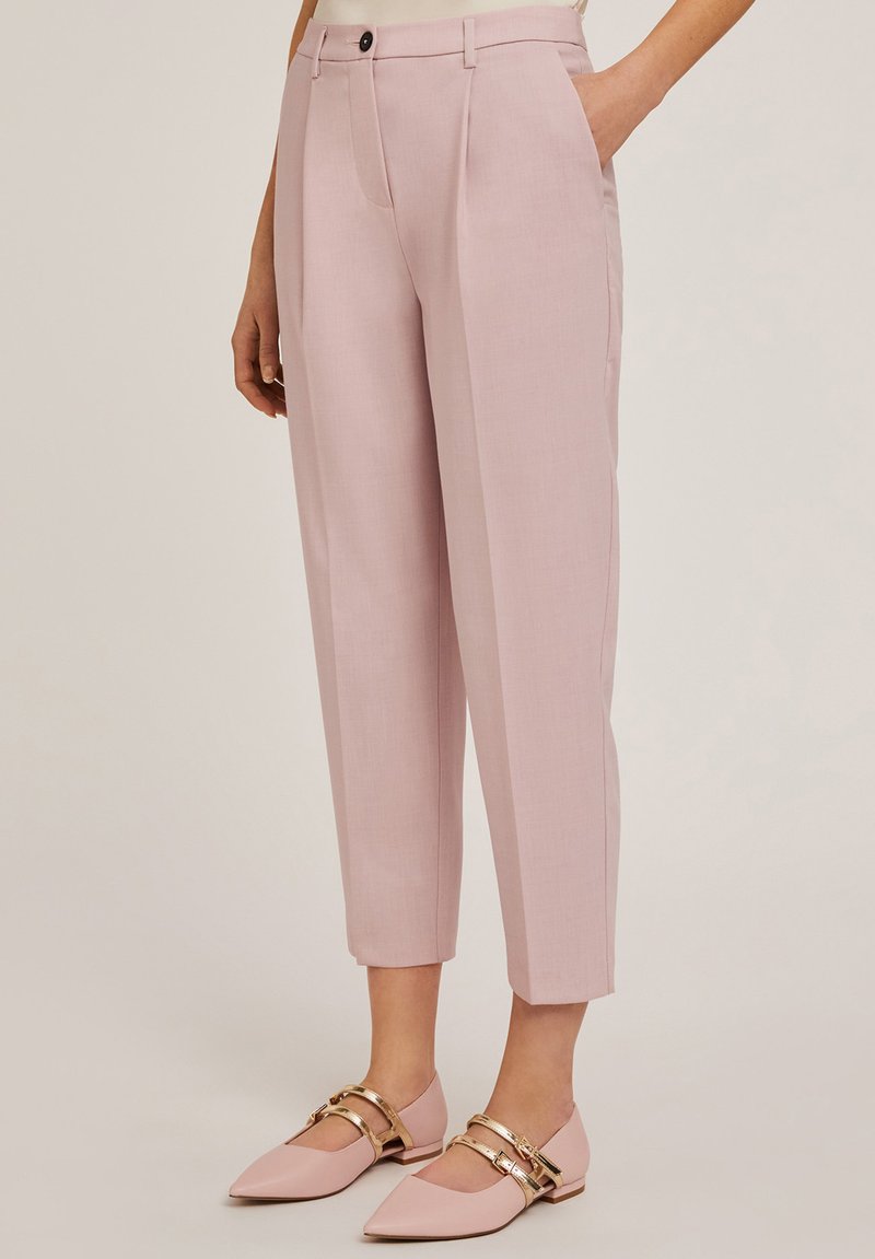 Pantalons taillés roses avec une coupe droite, dotés de poches latérales et d'un plis avant. Associés à des ballerines rose pâle et des accents en métal doré.