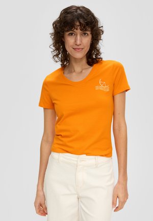 T-shirt en coton orange avec un col rond et des manches courtes, arborant un texte graphique blanc et un design de tranche de citron sur la poitrine.