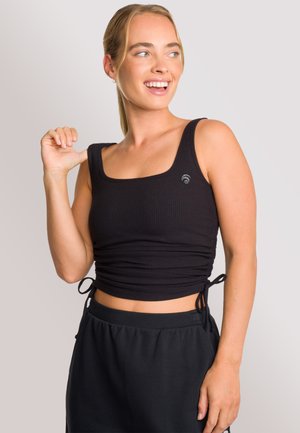 Black ribbed cropped tank top with square neckline and adjustable side ties. Features a small logo on the left side, paired with black bottoms.