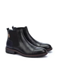 Botas Chelsea de cuero negro con paneles elásticos laterales y punta redonda. Presentan un capuchón de talón azul en contraste y un acento marrón en la suela.