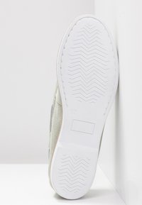 Semelle en caoutchouc blanche d'une chaussure décontractée avec un motif de bande de roulement en zigzag, taille 37 marquée près du centre, présentée sur un fond blanc.