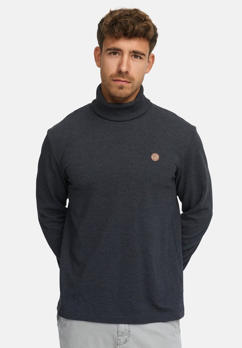 Dunkelgrauer Rollkragenpullover mit strukturiertem Finish. Mit einem kleinen runden Logo auf der Brust. Lange Ärmel und lockere Passform.