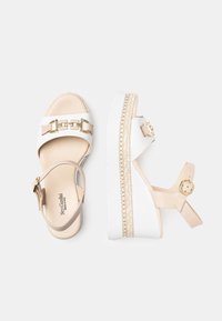 Sandali platform con cinturini sintetici bianchi e beige, dettagli in catena dorata e una suola bianca texturizzata ispirata al design espadrilles.