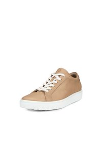Beige lädersneakers med vit gummisula, platta snören, rund tå och texturerade sidopaneler. Minimalistisk design med en neutral färgskala.