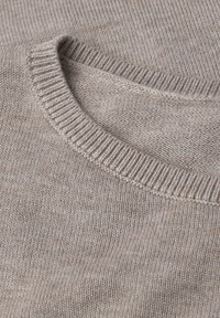 Beżowy sweter dzianinowy z prążkowanym okrągłym dekoltem i miękką teksturą, prezentujący delikatny melanżowy wzór na całej powierzchni.