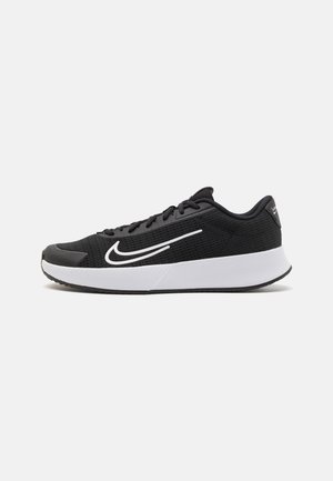 Baskets de sport noires avec une tige en mesh, logo et accents blancs, semelle rembourrée et semelle extérieure en caoutchouc texturé pour une bonne adhérence.
