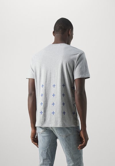 Grå bomullströja med korta ärmar, med ett blått plussymbol-mönster på ryggen. Sittande design, avslappnad stil och mjuk textur.