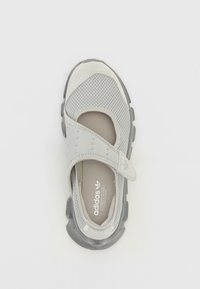 Scarpa sportiva grigia con tomaia in rete, cinturino regolabile e suola in gomma grigia. Presenta il logo sulla soletta e dettagli testurizzati sui lati.