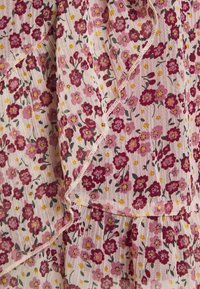 Tessuto leggero caratterizzato da uno sfondo rosa con piccoli motivi floreali multicolori in rosso scuro e giallo. I bordi sono rifiniti con delicate cuciture.