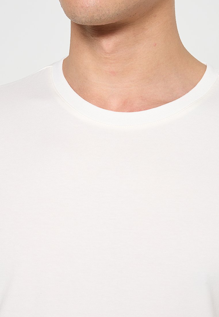 Biała, krótko rękawowa koszulka z okrągłym dekoltem, wykonana z miękkiej bawełny, charakteryzująca się gładką strukturą i minimalistycznym wzornictwem.