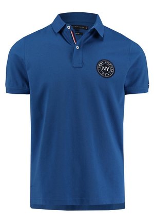 Polo bleu à manches courtes avec col, patte à deux boutons et logo circulaire "Tommy Hilfiger NY U.S.A." sur la poitrine gauche.
