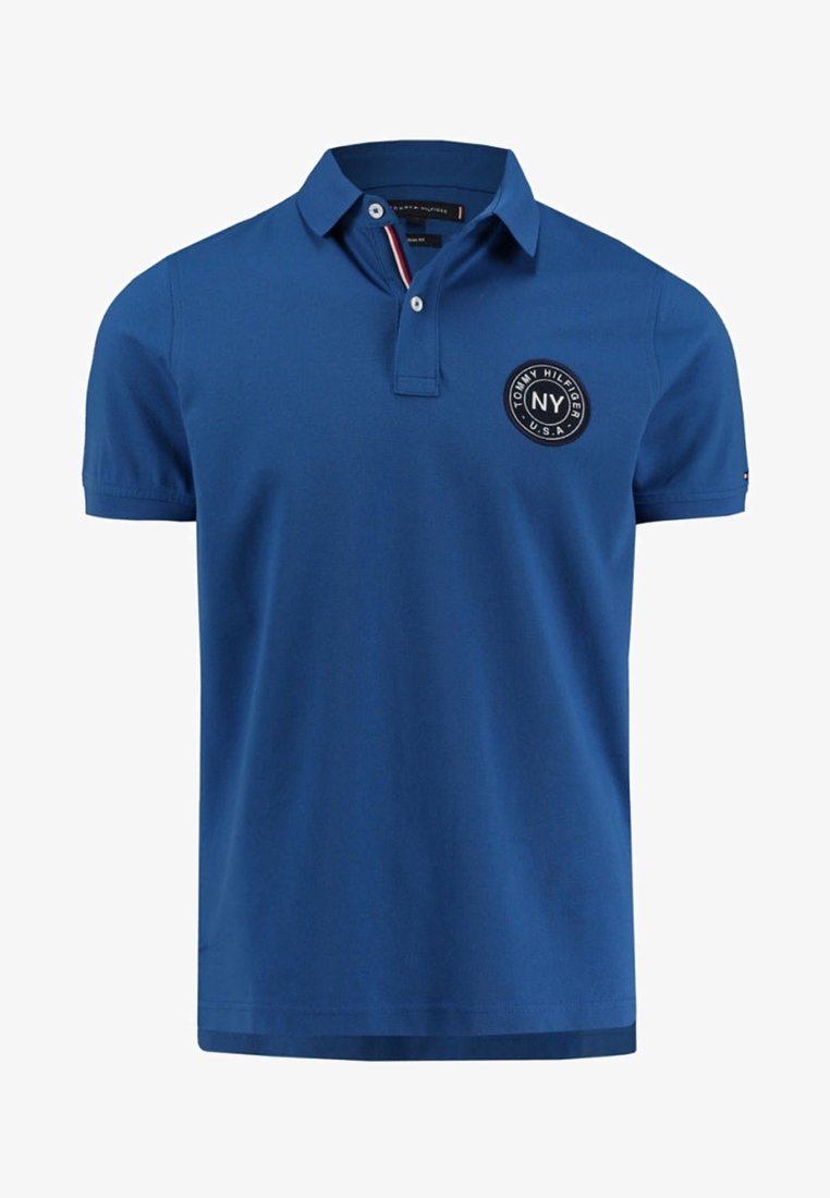 Polo bleu à manches courtes avec col, patte à deux boutons et logo circulaire "Tommy Hilfiger NY U.S.A." sur la poitrine gauche.