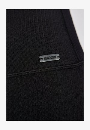 Schwarzer gerippter Stoff mit einer strukturierten Oberfläche und einem kleinen, grauen SNOCKS-Etikett, das an der Naht angenäht ist. Minimalistisches Design ohne zusätzliche Details.