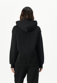 Black hooded sweatshirt with a relaxed fit, soft cotton fabric, ribbed cuffs, and hem. Features a center seam detail on the back.
