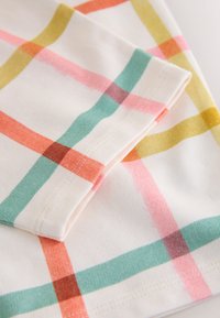 Bijela tkanina s uzorkom mreže širokih, mekanih pastelnih pruga u narančastoj, roze, zelenoj i žutoj boji, prikazujući savijeni kut s vidljivim šavovima.