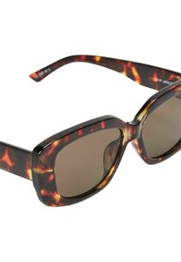 Lunettes de soleil en écaille de tortue avec des verres bruns, monture carrée, finition brillante, et un design épais. Les branches s'inclinent légèrement vers l'extérieur.