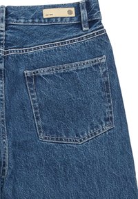 Denim jeans with a mid-rise waist, blue color, classic five-pocket design, visible stitching, and a small label on the waistband.