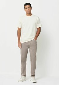 Kreem lühikeste varrukatega T-särk, millele on sobitatud heledast hallist kangast püksid, omades klassikalist lõiget. Valged tossud täiustavad komplekti. Sile kangakoe tekstuur.