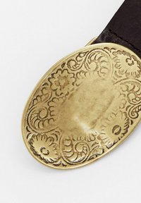 Ovale Messinggürtelschnalle mit geprägten floralen und scrolling Mustern, die an einem dunkelbraunen Lederband befestigt ist.