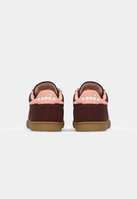 Brown and pink suede sneakers with a rubber sole, featuring a stitched logo on the back and a cushioned collar for comfort.