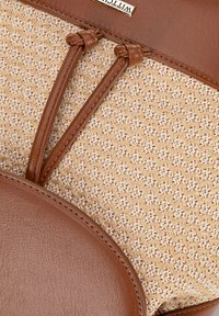 Cuir brun et matériau tissé beige, avec une base ronde et deux sangles en cuir. La texture est lisse avec un motif tissé contrastant.