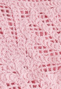 Tissu au crochet rose doux montrant des motifs détaillés de points floraux et en treillis avec des boucles de fil texturées et surélevées.