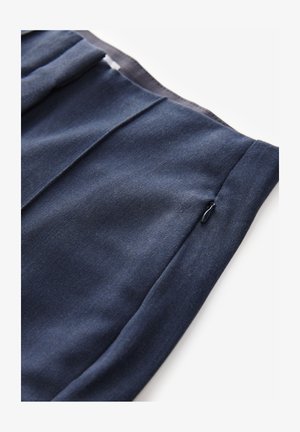 Námorně modrá látka s hladkým povrchem a diagonálním švem. Obsahuje skrytý zip kapsu, což ukazuje na čistý a upravený design.