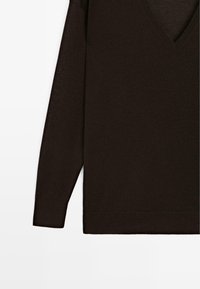 Pull en tricot marron foncé avec un col en V et des manches longues. Texture lisse et poignets côtelés. Style minimaliste sans motifs visibles.