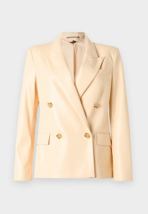 Bež blazer s dvostrukim gumbima s sijočim završetkom, izrezanim reverima, gumbima u zlatnoj boji i dva prednja džepa. Napravljen od glatke tkanine.