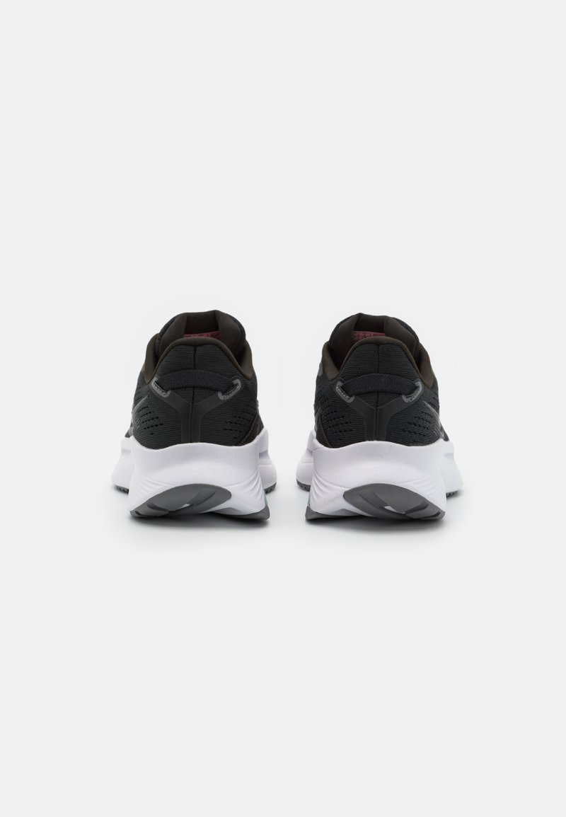 Un paio di scarpe sportive nere e bianche viste dal retro su uno sfondo bianco semplice.
